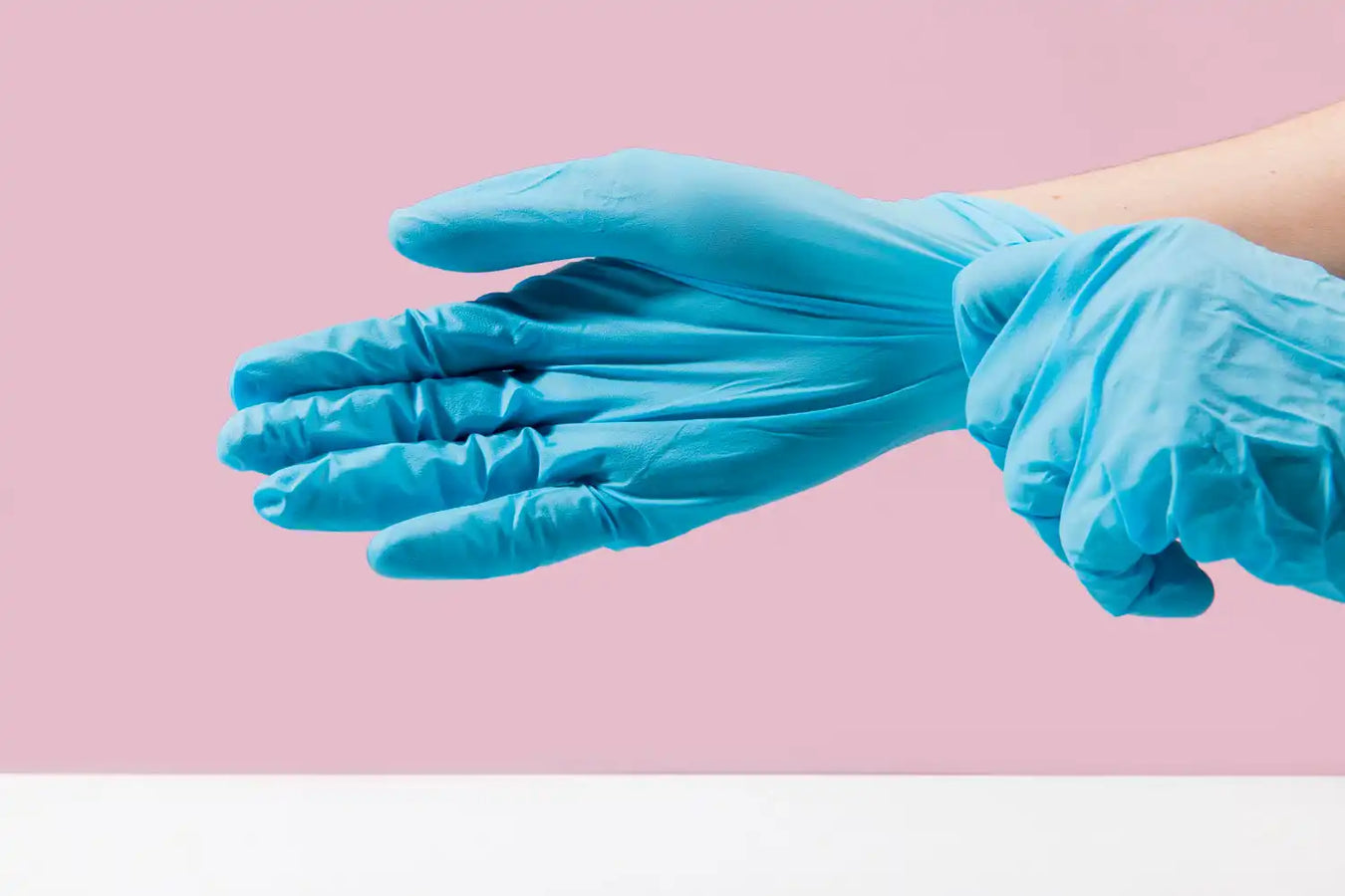 Blue latex or nitrile medical glove being put on a hand.