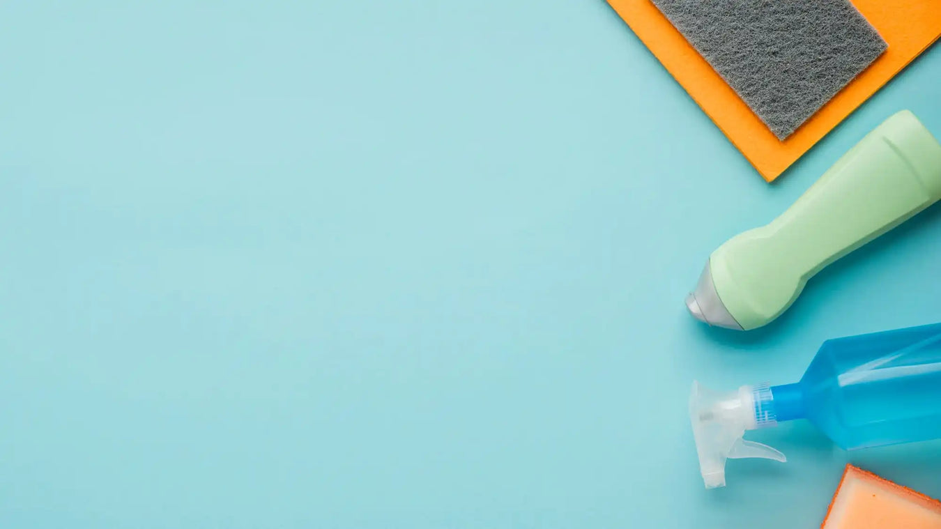 Cleaning supplies and sponges arranged on a turquoise surface.